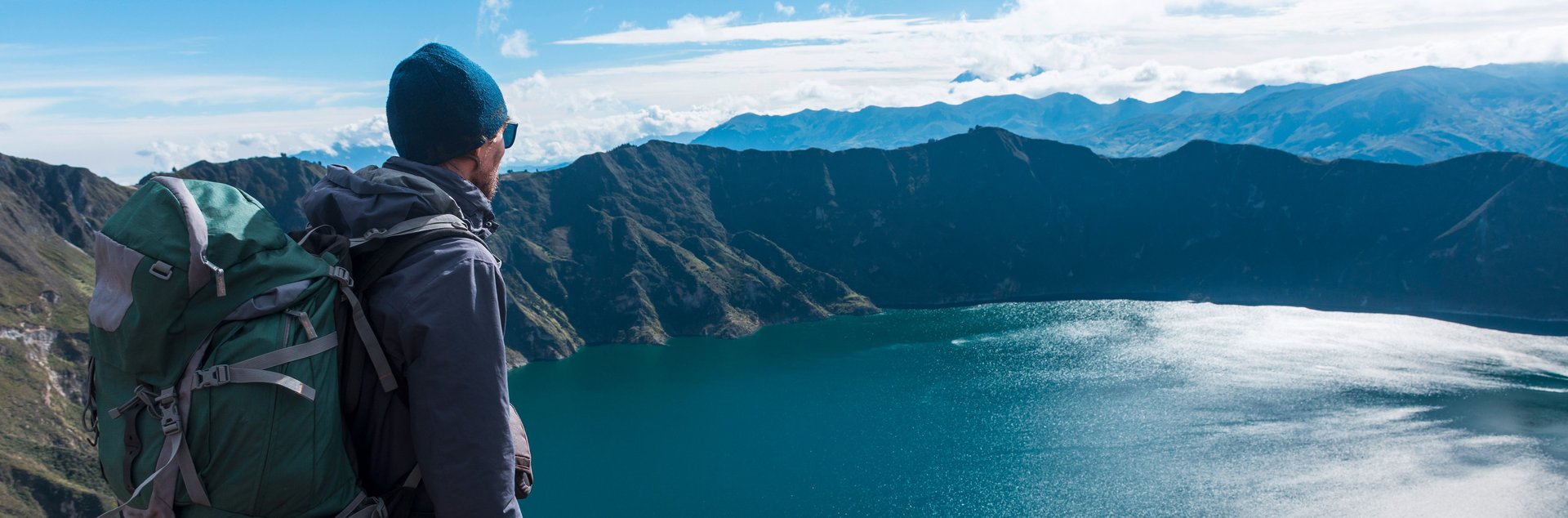 Ein Mann blickt von oben auf einen Bergsee
