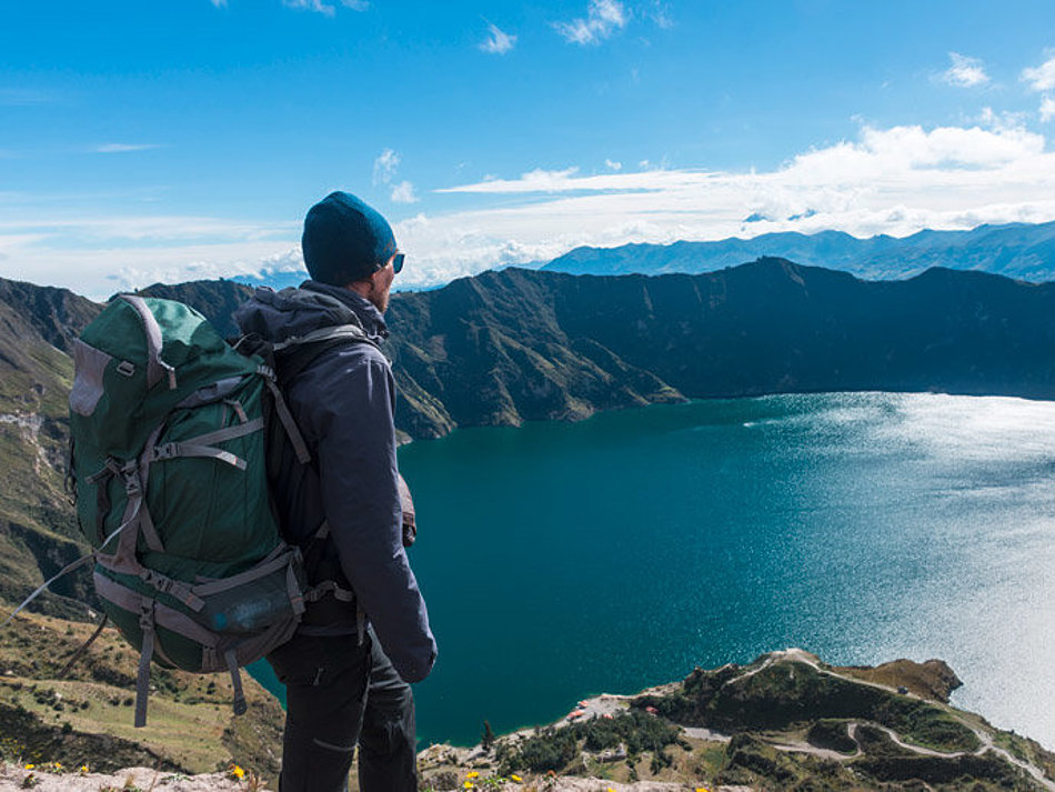 A man looks down on a mountain lake from above