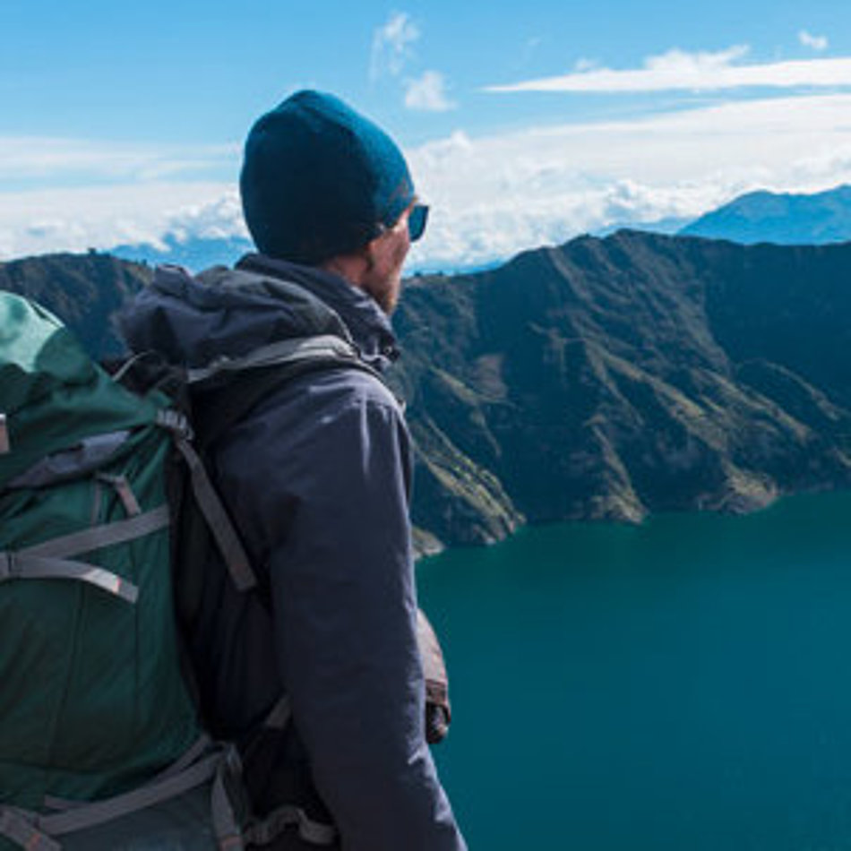 A man looks down on a mountain lake from above