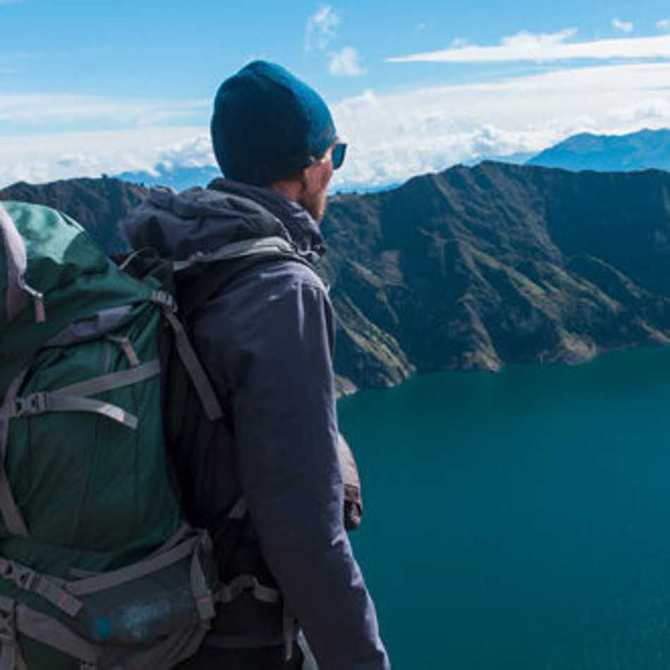 Ein Mann blickt von oben auf einen Bergsee