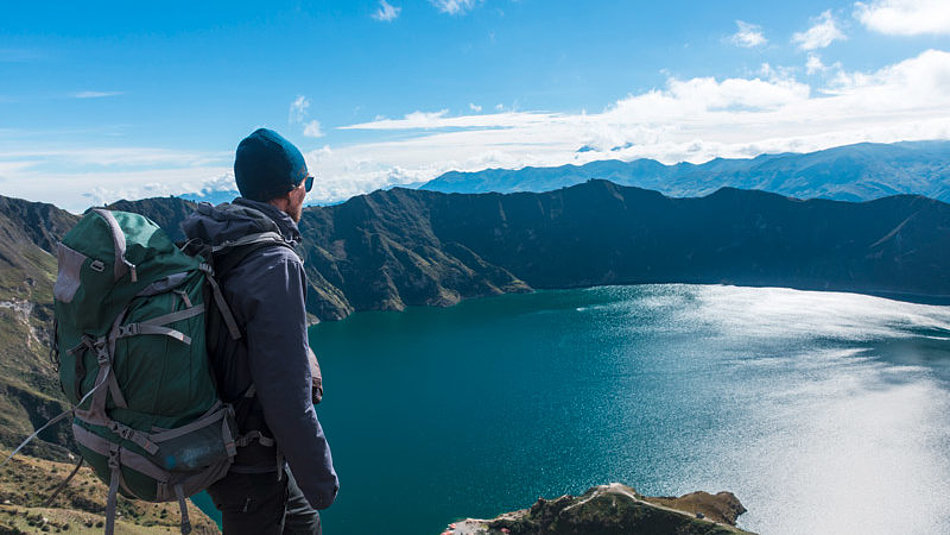 Ein Mann blickt von oben auf einen Bergsee