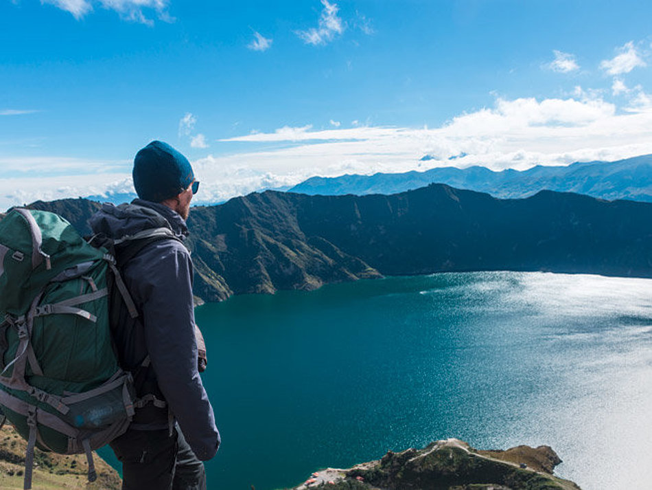 Ein Mann blickt von oben auf einen Bergsee