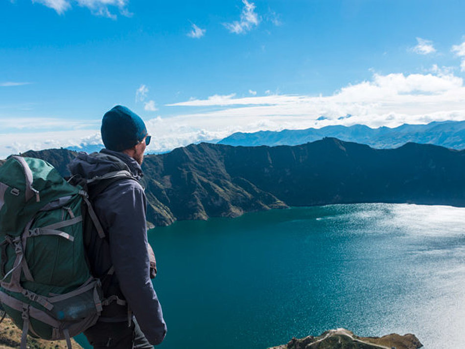 Ein Mann blickt von oben auf einen Bergsee