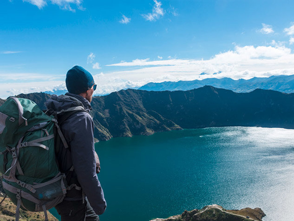 A man looks down on a mountain lake from above