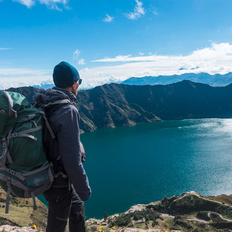 Ein Mann blickt von oben auf einen Bergsee