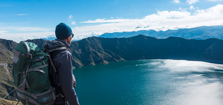 Ein Mann blickt von oben auf einen Bergsee