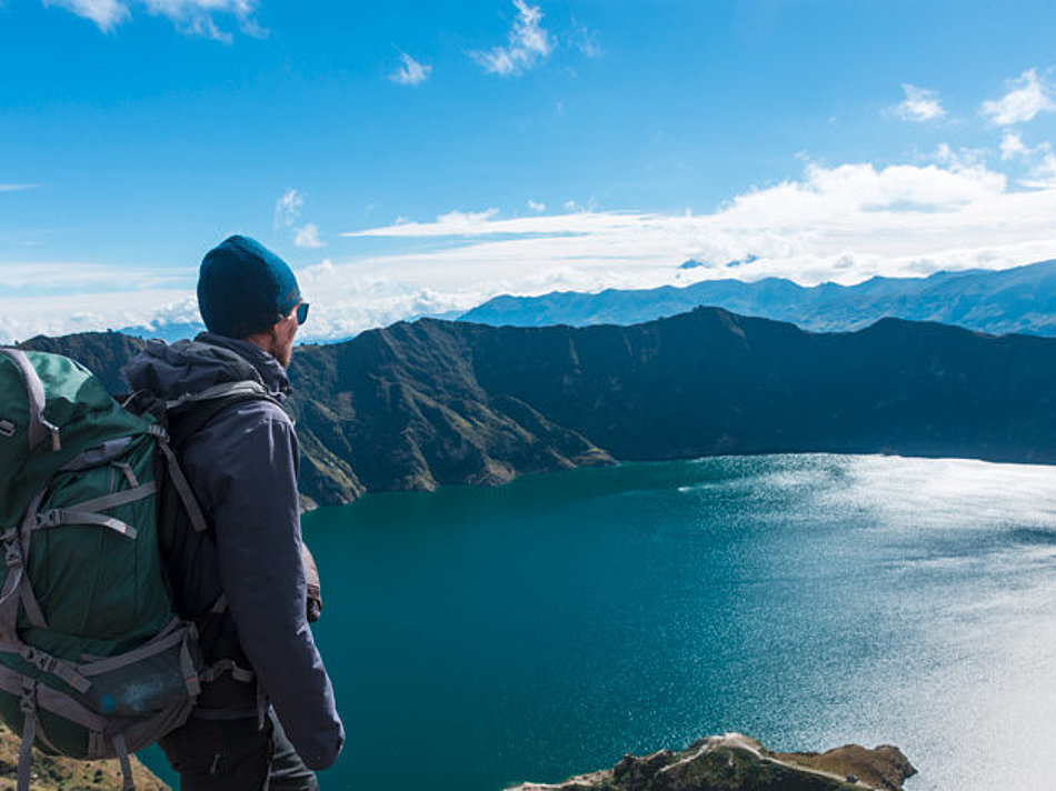 A man looks down on a mountain lake from above