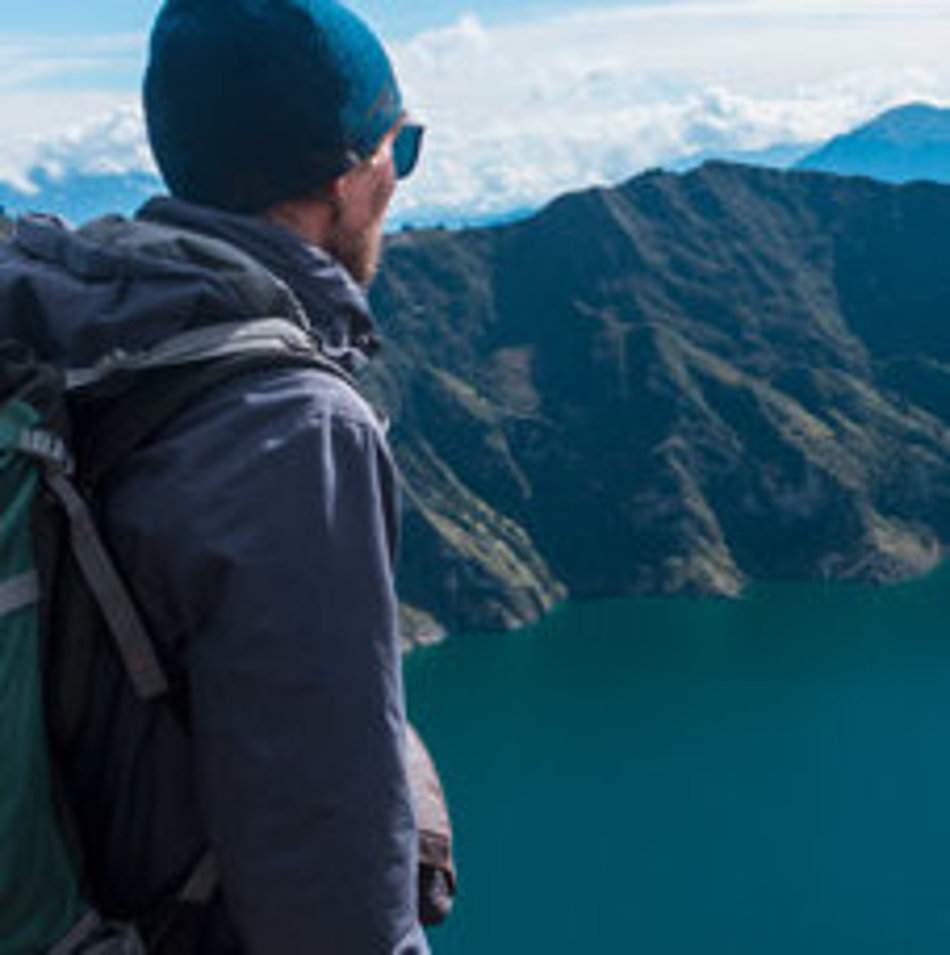 A man looks down on a mountain lake from above