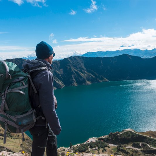 Ein Mann blickt von oben auf einen Bergsee