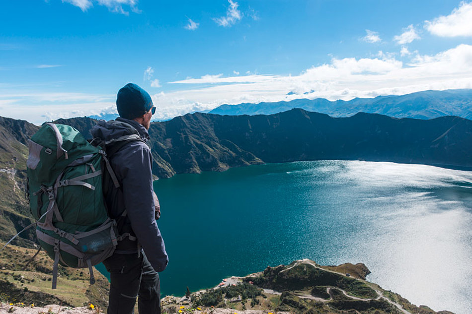 A man looks down on a mountain lake from above