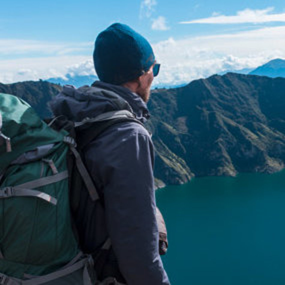 Ein Mann blickt von oben auf einen Bergsee