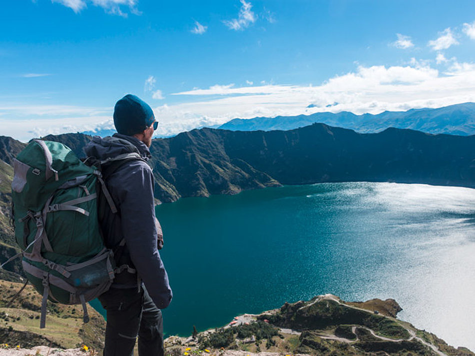 Ein Mann blickt von oben auf einen Bergsee