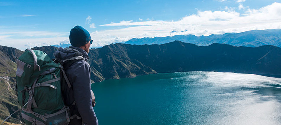 A man looks down on a mountain lake from above