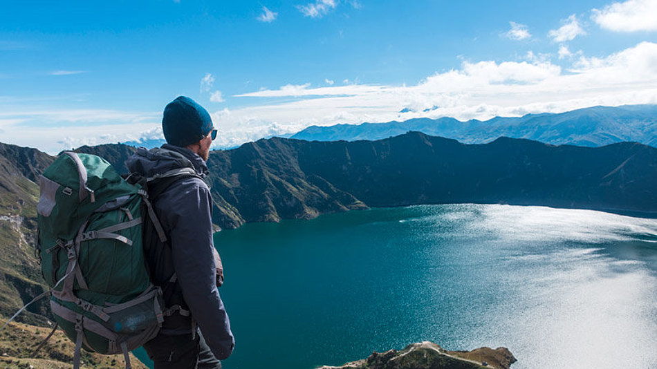 A man looks down on a mountain lake from above