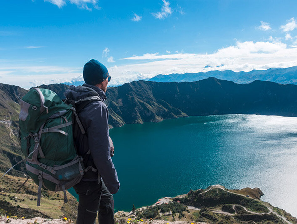 Ein Mann blickt von oben auf einen Bergsee