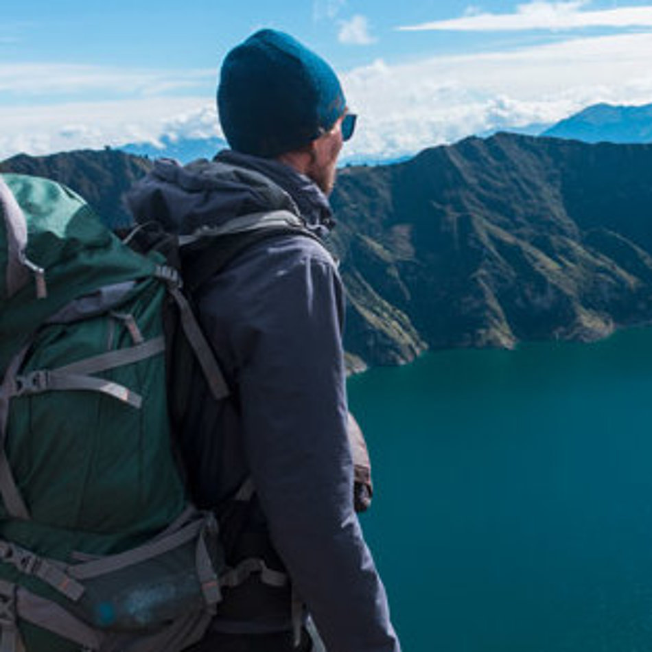 A man looks down on a mountain lake from above