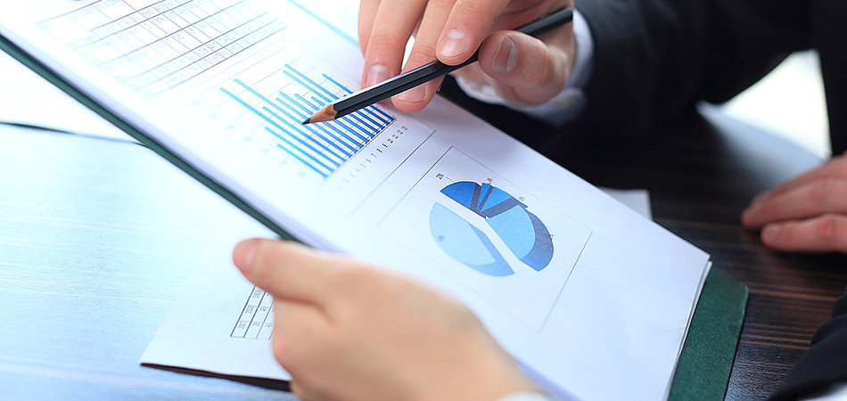 A person pointing at a printed chart with a pencil